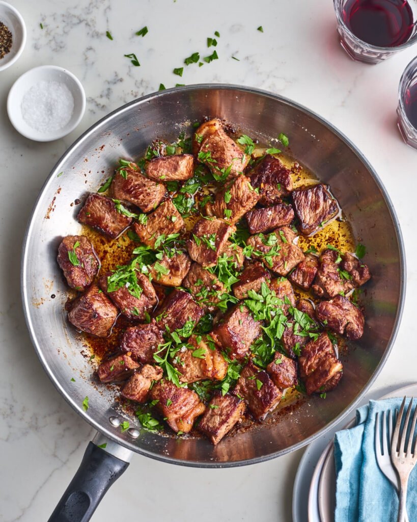 beef cubes with herbs and spices in a pan