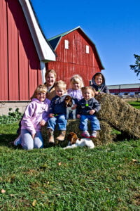 kilgus kids in front of red barn with baby goats