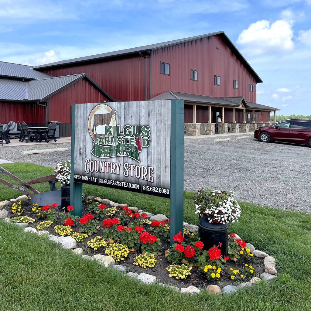 bright sunny day outside the new Kilgus Farmstead Country Store with sign and blooming flowers